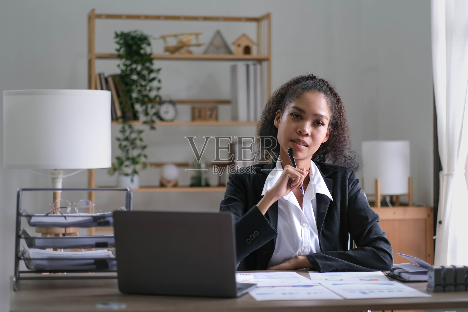 富有创造力的年轻非裔美国妇女在她的工作室用笔记本电脑工作，做会计分析报告房地产投资数据，财务和税收系统的概念。照片摄影图片