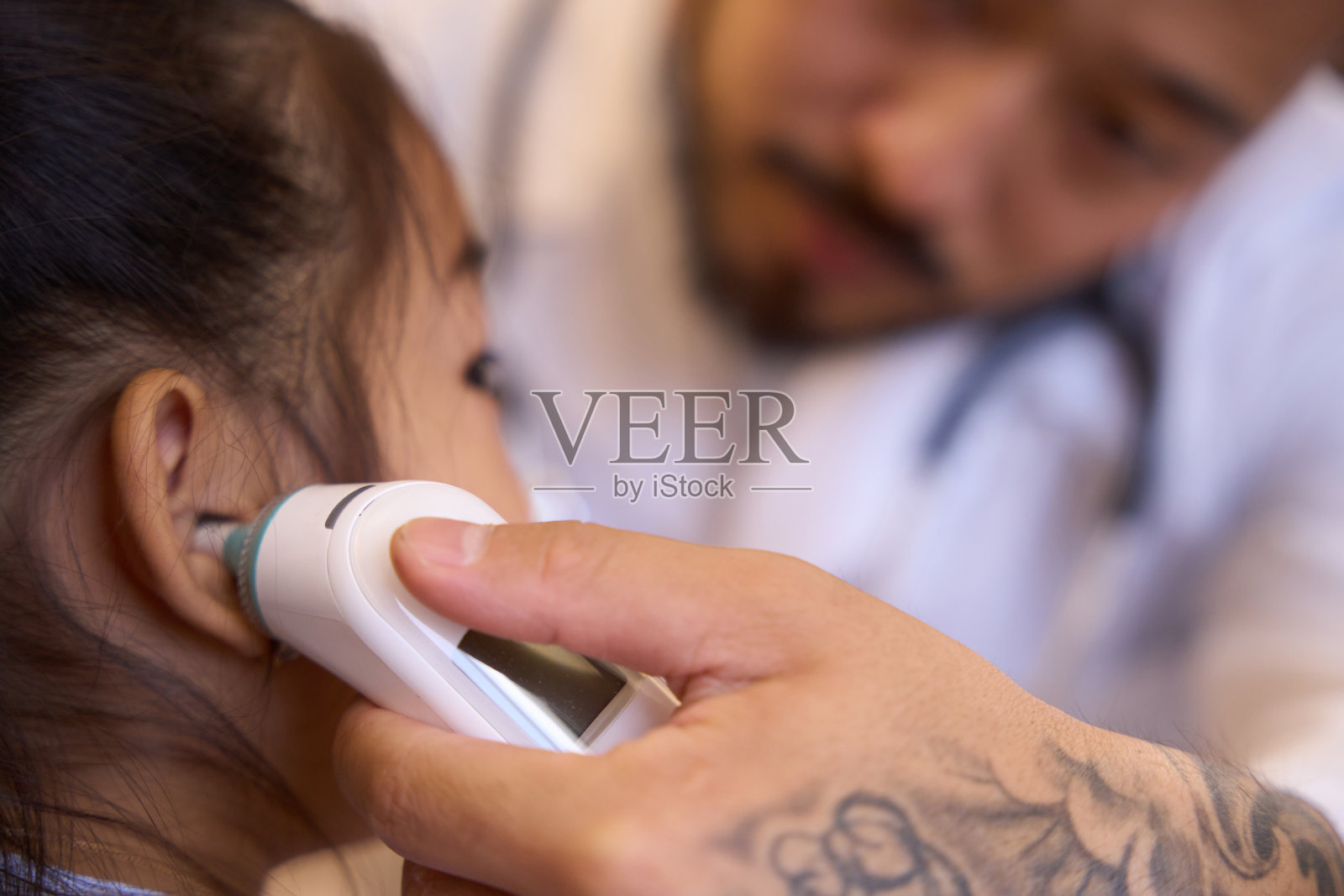 耳鼻喉科医生通过耳镜观察一个小女孩的耳朵照片摄影图片