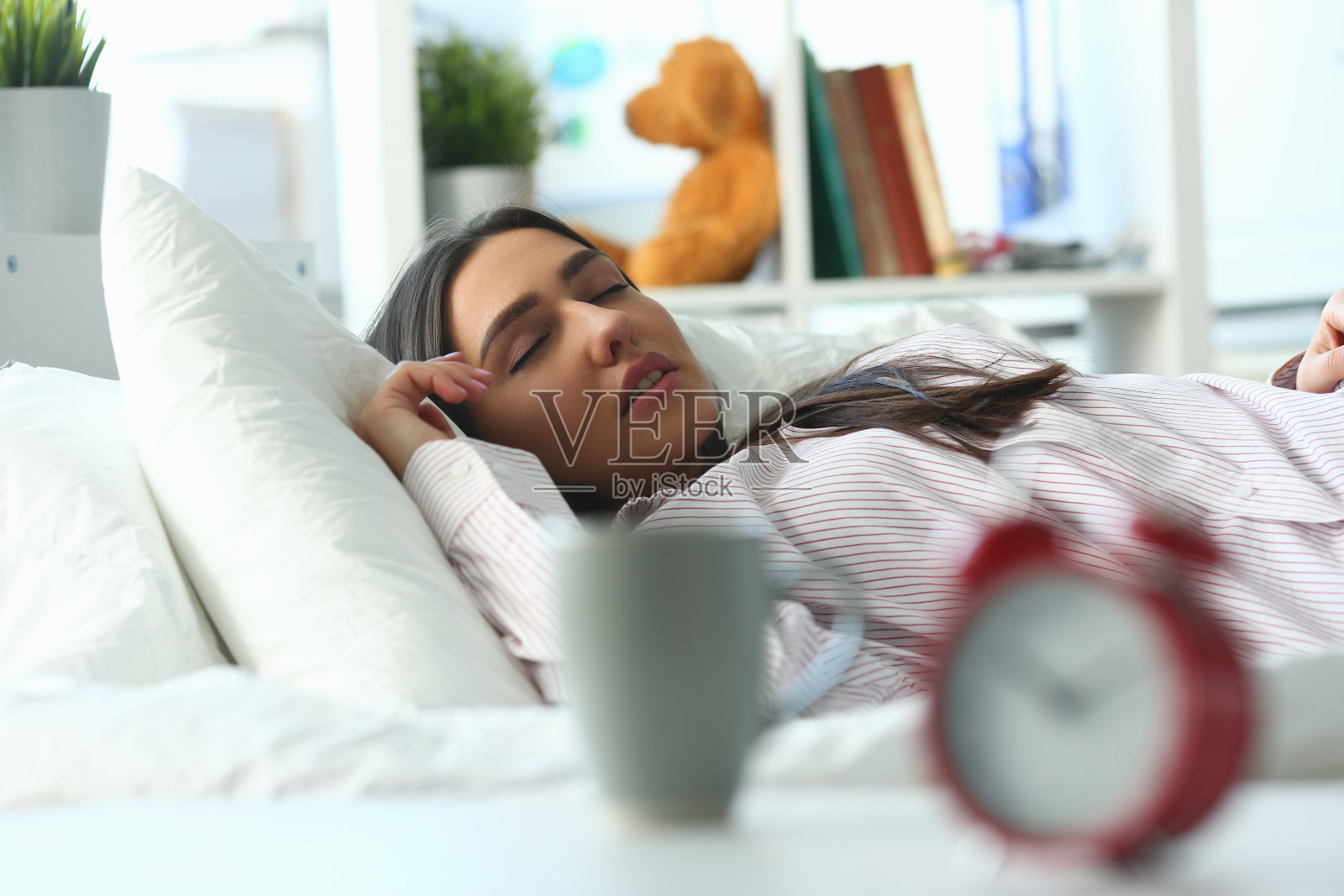 红色闹钟的特写和安静的年轻女子睡在床上的背景照片摄影图片