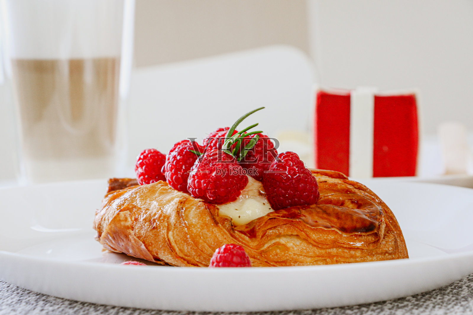 美味的覆盆子和奶油蛋挞放在白色的盘子上，背景是咖啡照片摄影图片