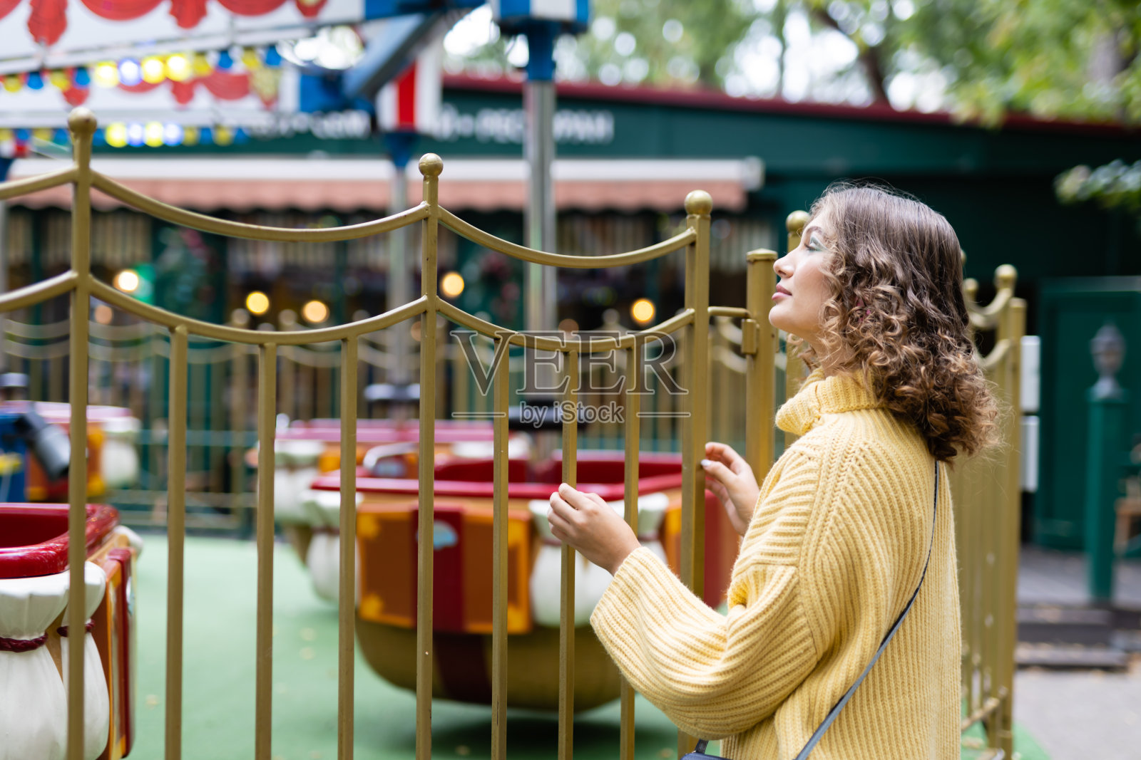 游乐园里的女人看着旋转木马，开心地笑着，这是周末的概念照片摄影图片