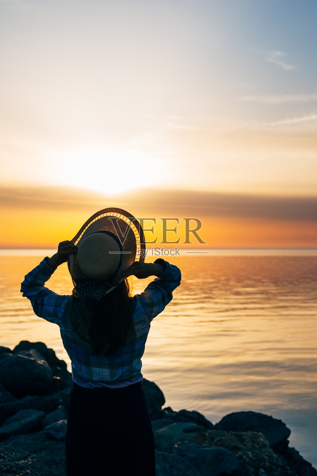 一个女人的特写肖像，从后面夏天的帽子在日落的海上，海洋在旅行照片摄影图片