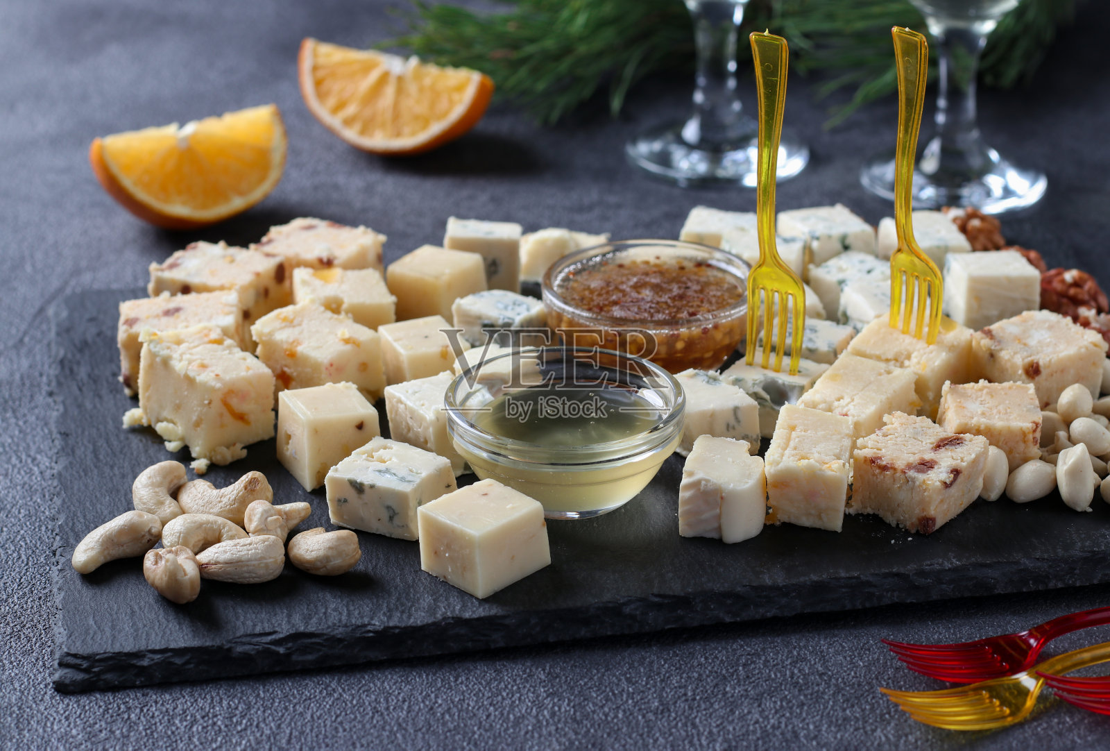 各种各样的精英奶酪放在石板上，背景是黑色的。酒会的零食。照片摄影图片