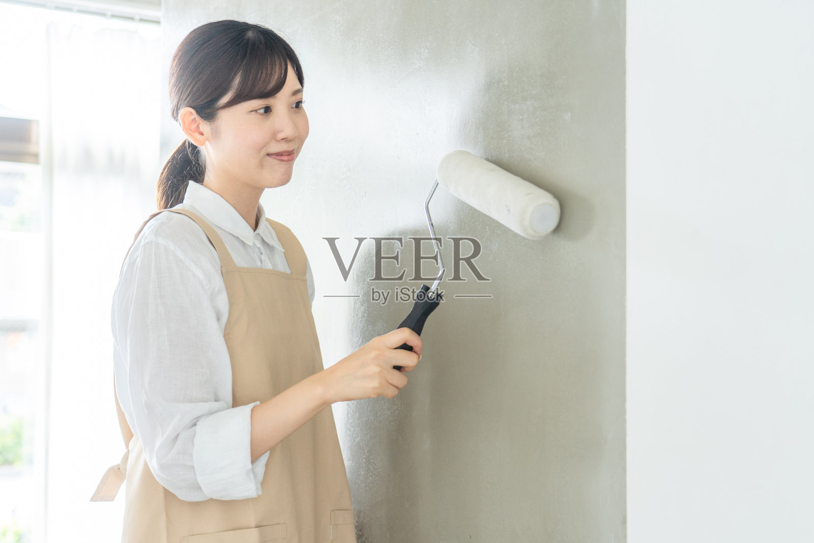 在房间里刷墙的女人照片摄影图片