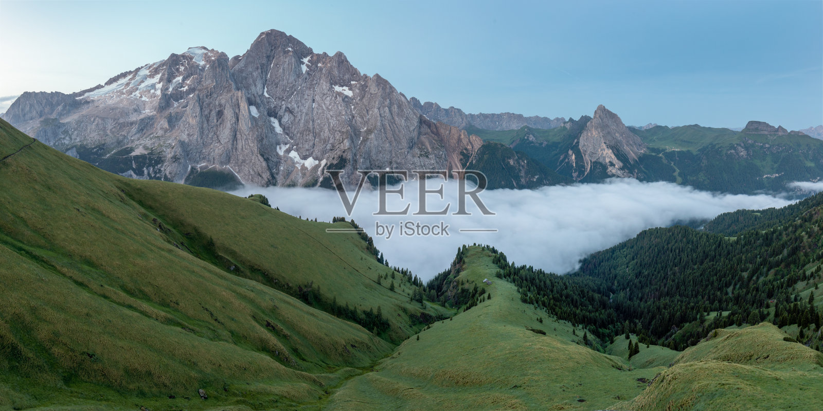 夏天的马尔莫拉达(蓬塔佩尼亚)，意大利白云石的最高峰。多洛米蒂的高山景观，可以看到马尔莫拉达的冰川和美丽的绿色草地，草地上开着黄色的花。照片摄影图片