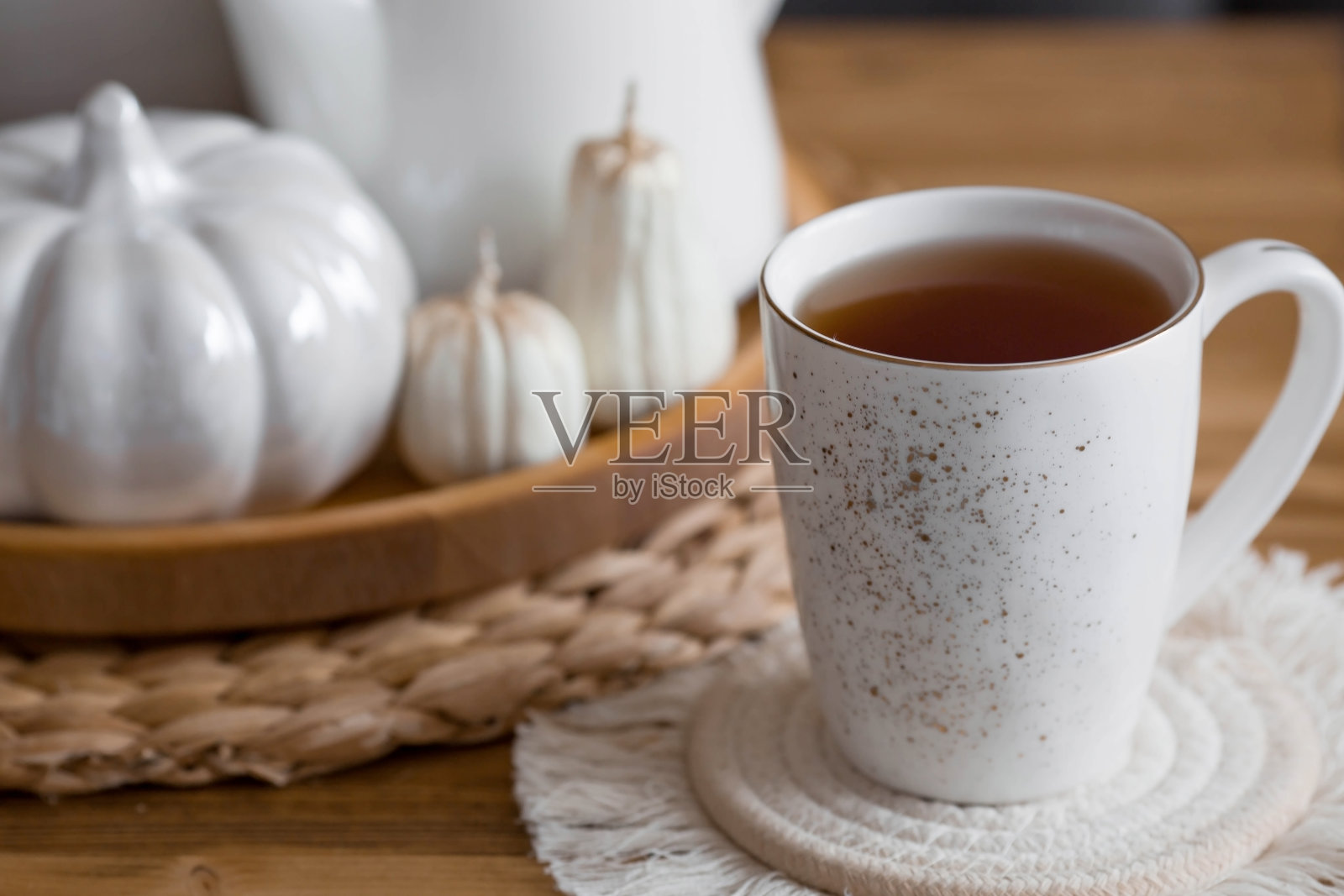 静物。干潘帕斯草插在花瓶里，白色陶瓷南瓜，一个茶壶，一个杯子和南瓜形状的蜡烛放在客厅室内的咖啡桌上。舒适的秋天的概念。照片摄影图片