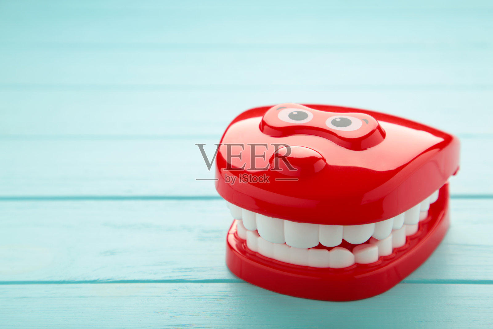 蓝色背景的塑料玩具牙齿。抽象的最小组成。照片摄影图片