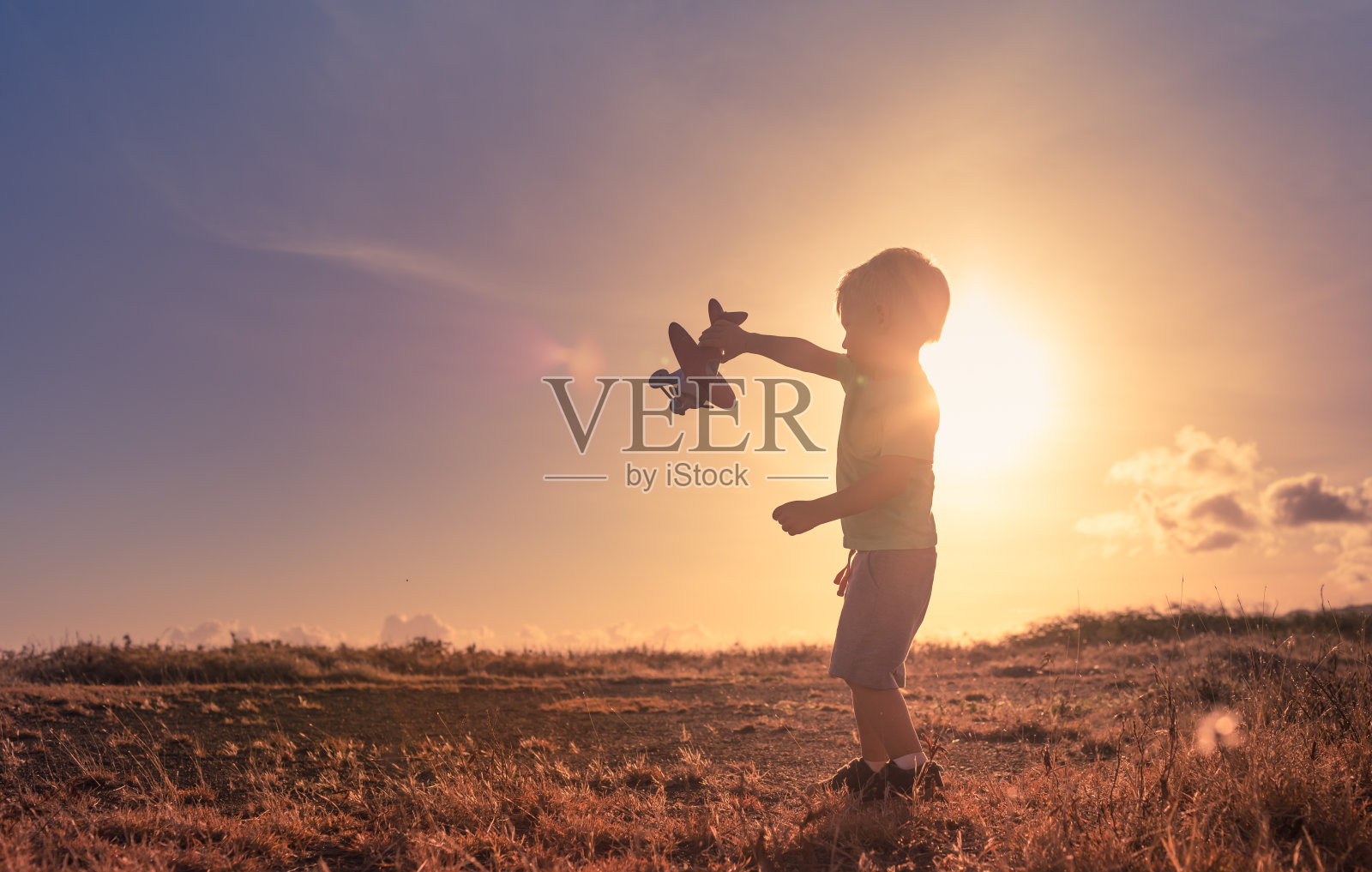 小男孩在草地上玩飞机。照片摄影图片