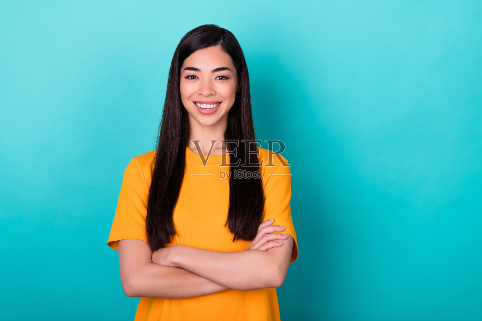 照片的有趣的深色长发女士交叉双手穿黄色t恤孤立在蓝绿色的背景照片摄影图片