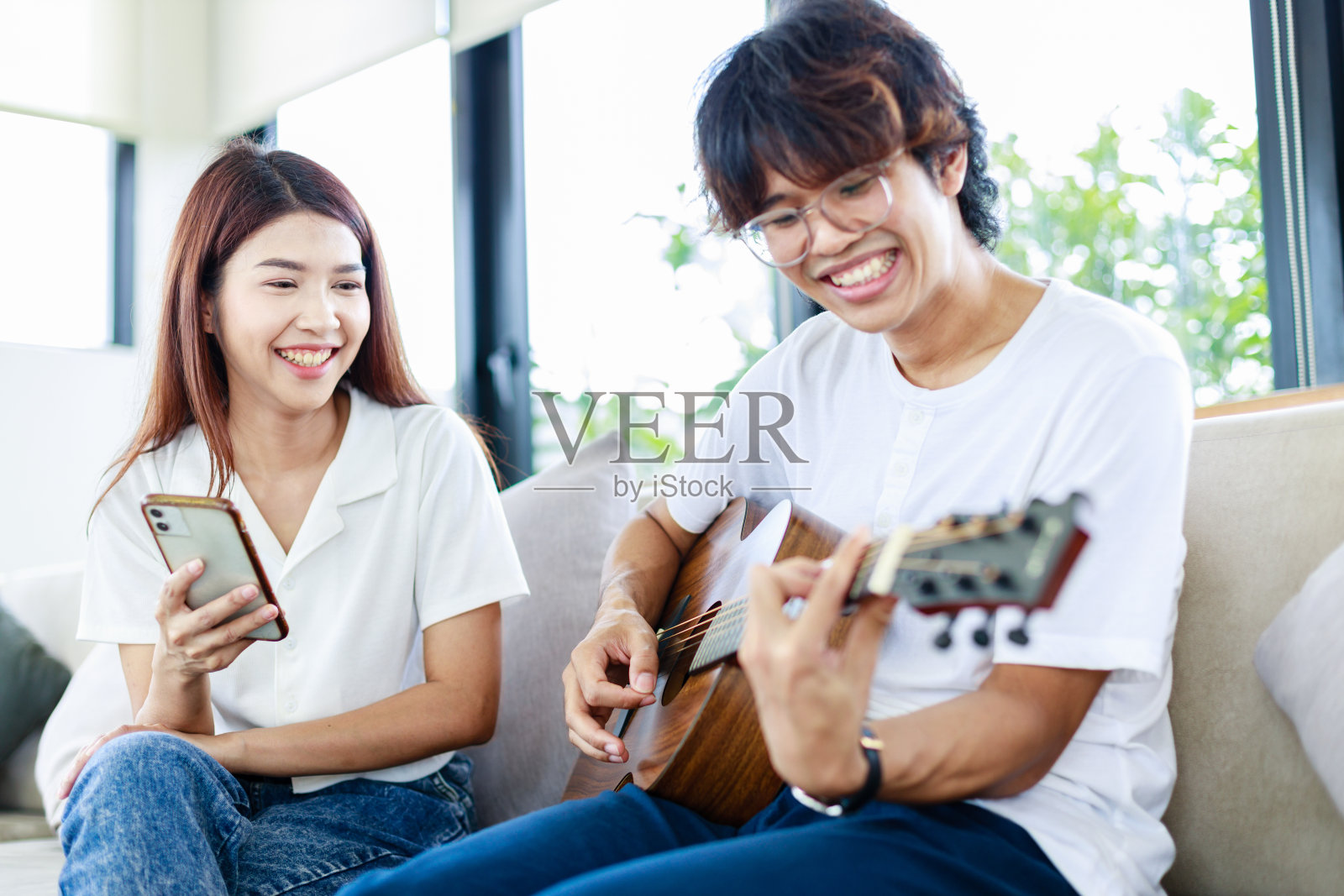 甜蜜的一对，年轻人弹吉他，女孩在客厅唱歌，休闲活动照片摄影图片