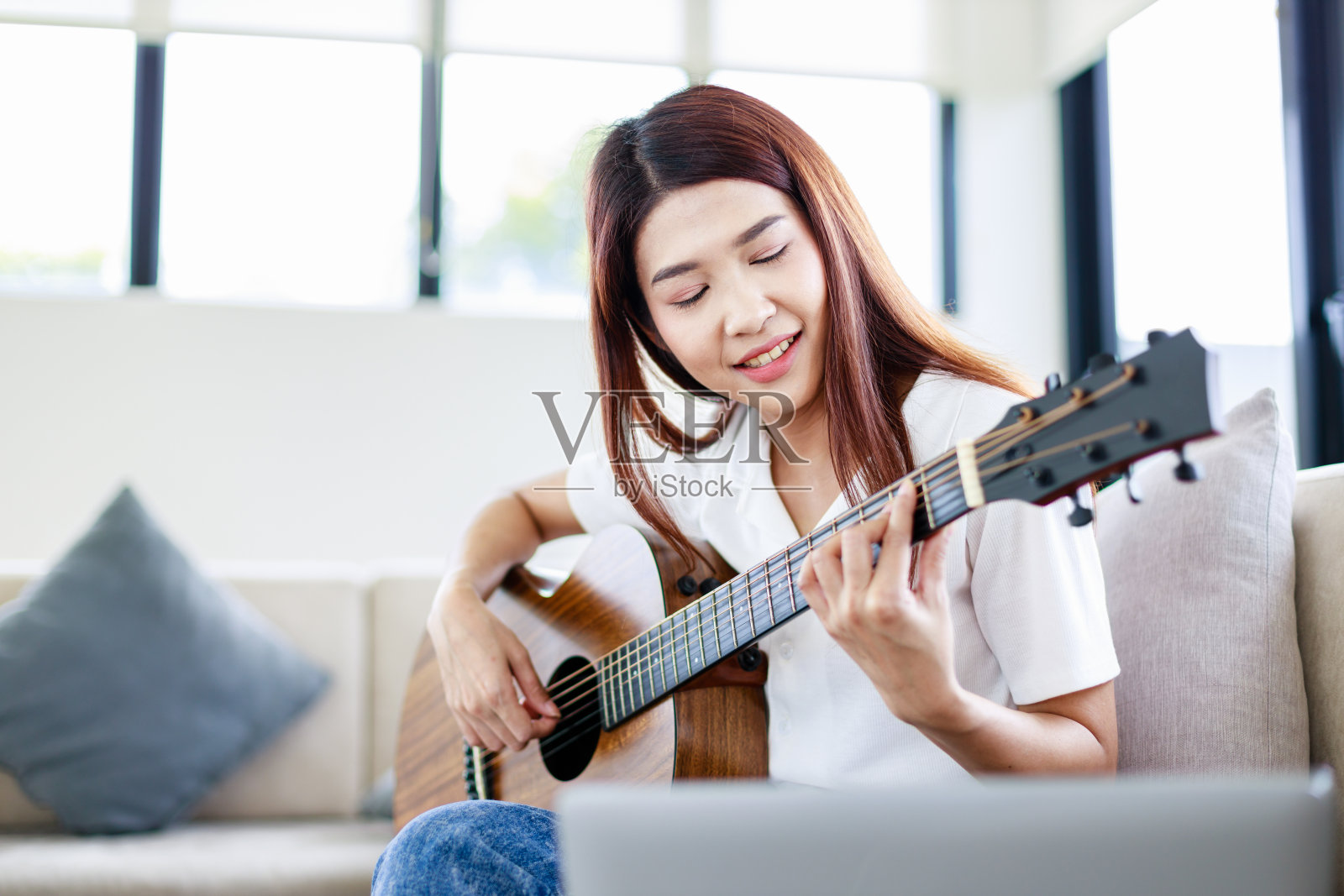 美丽的女子弹奏原声吉他，生活在吉他手音乐家的家中照片摄影图片