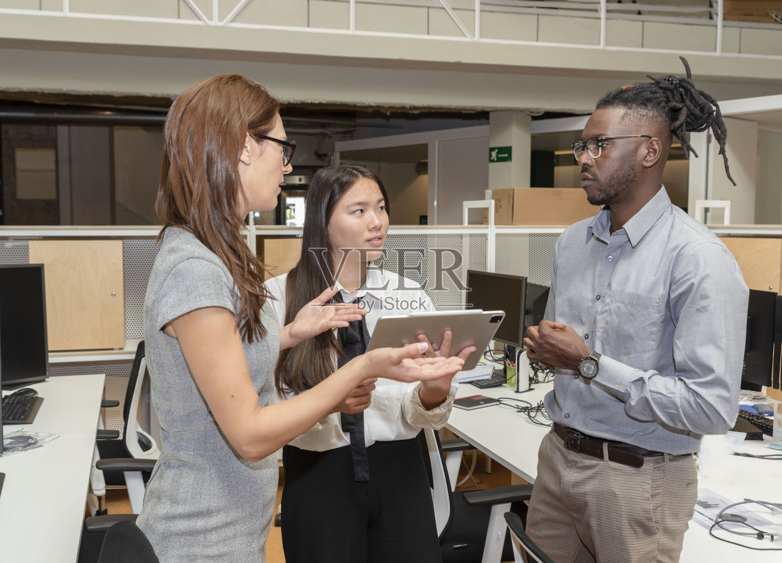 三个多民族的商务人士在办公室聊天，使用平板电脑照片摄影图片