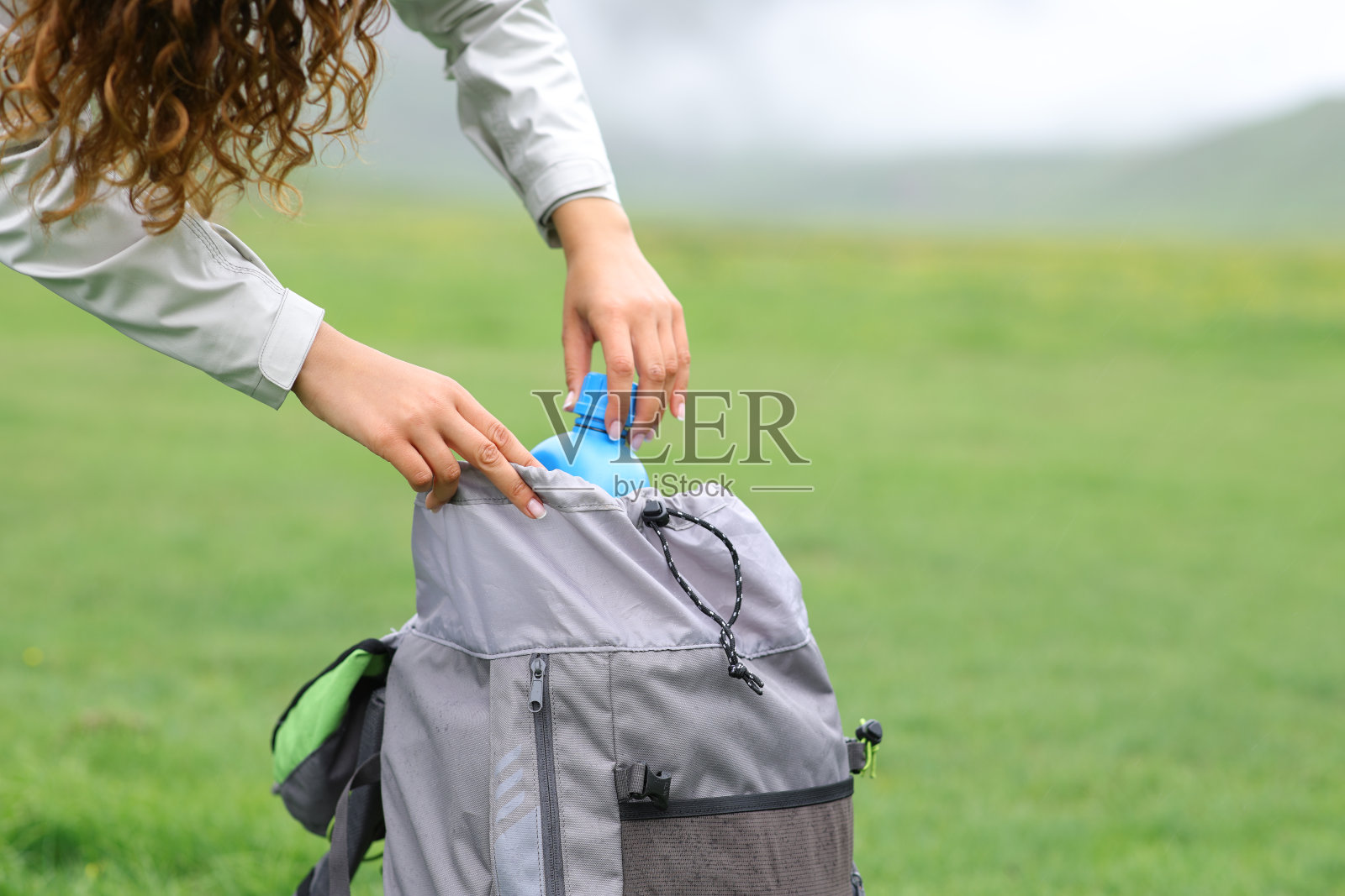 徒步旅行者将水壶放入背包中照片摄影图片