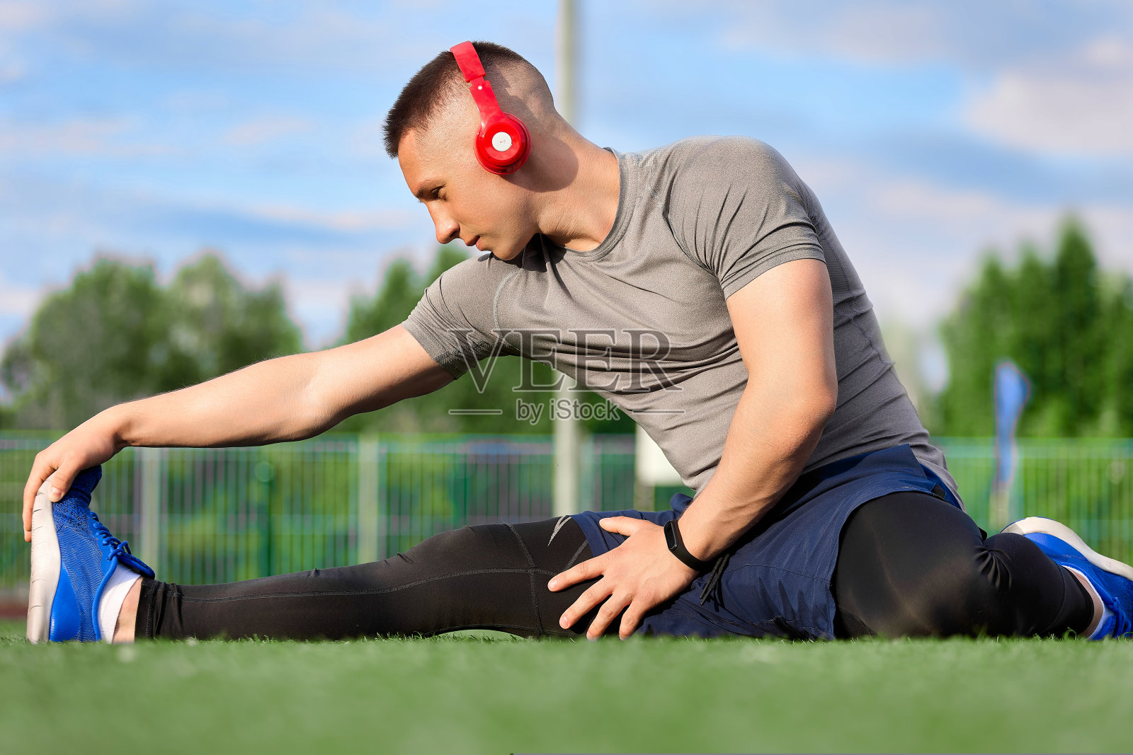 穿着蓝色运动鞋和运动服的运动员在做伸展运动照片摄影图片