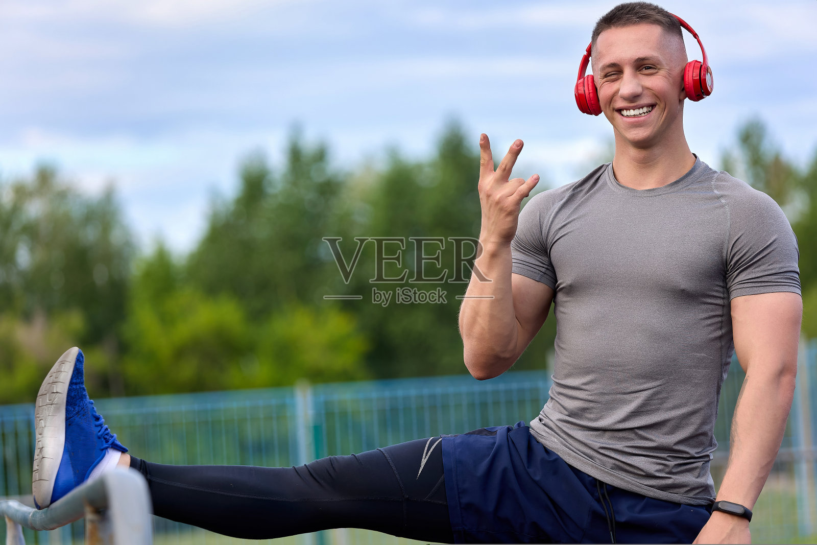 快乐的运动员一边伸伸腿，一边戴着耳机听音乐照片摄影图片