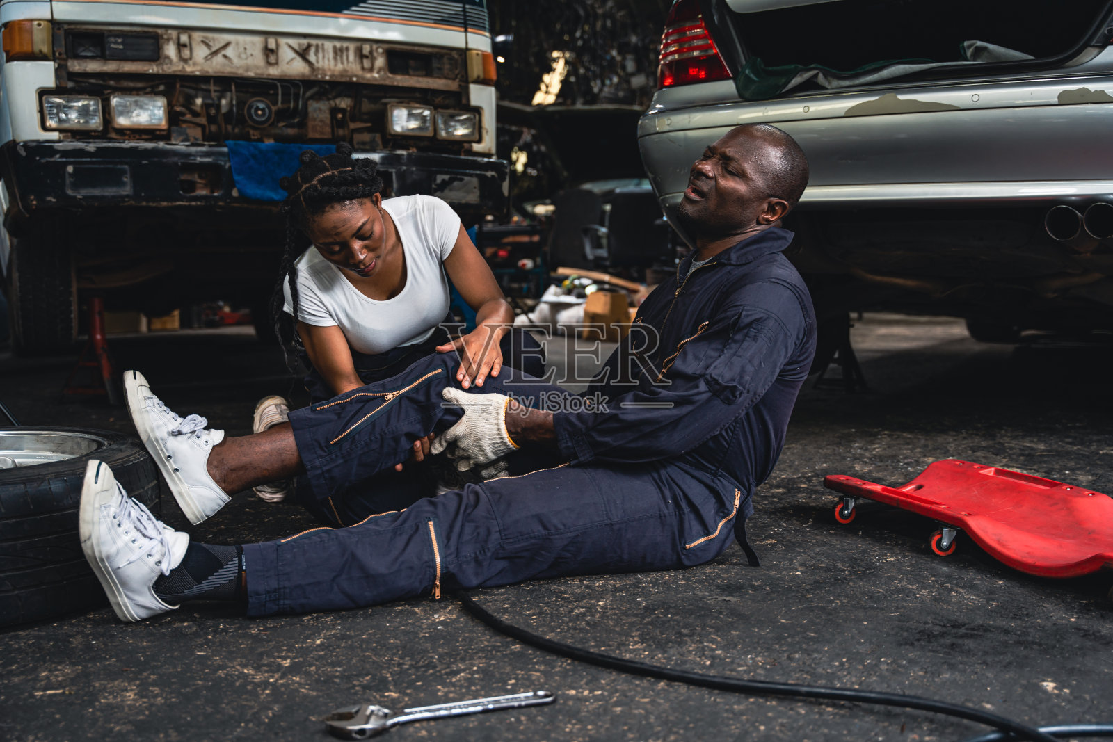 男机修工腿抽筋女机修工来急救。照片摄影图片