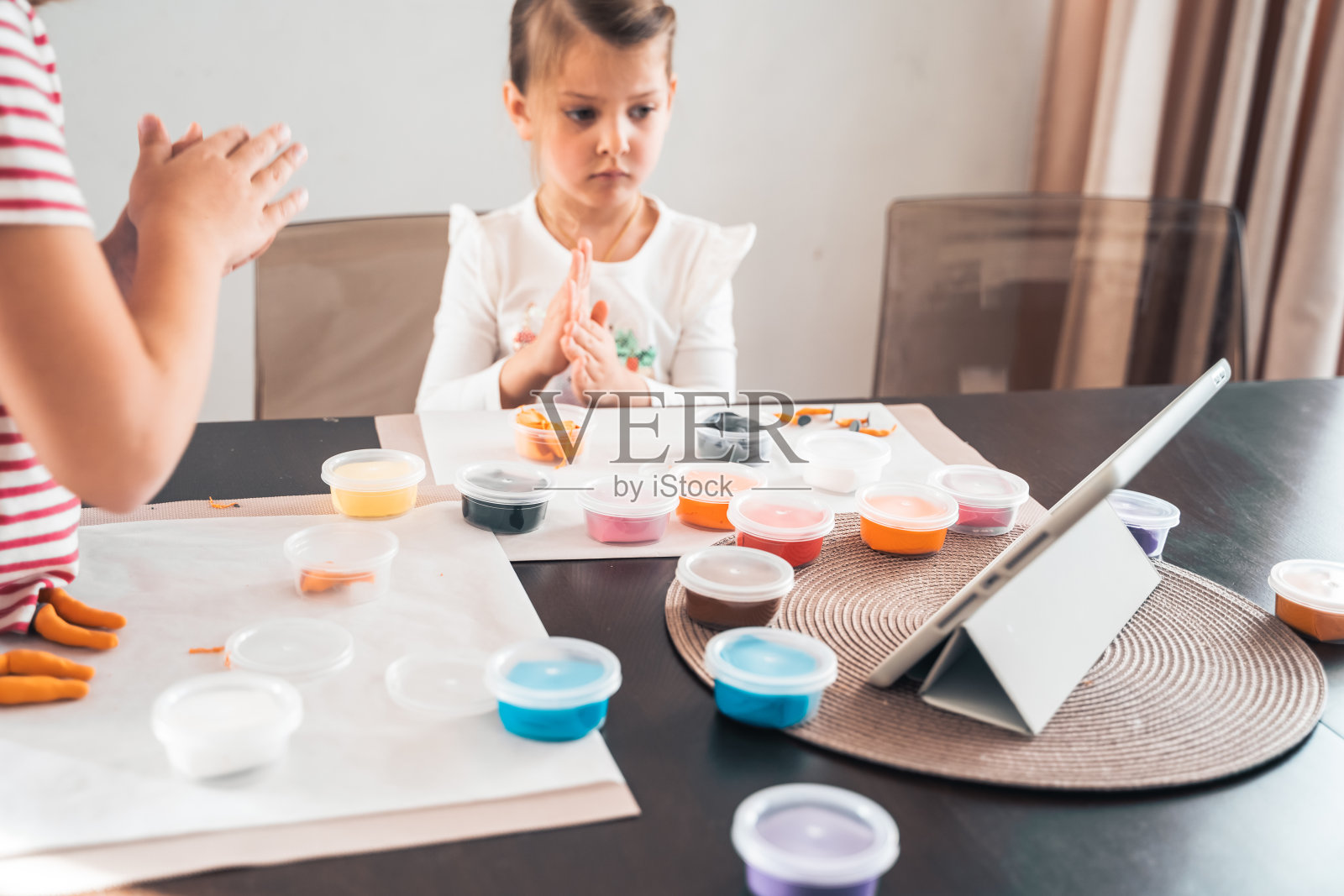 小女孩们用空气橡皮泥和面团雕刻小雕像。平板电脑在线课程。儿童的创造力，爱好，发展活动，训练，发展手部精细运动技能照片摄影图片