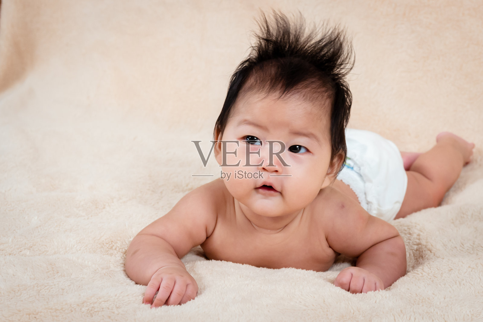 亚洲刚出生的女婴，躺在棕色的床上，孩子睡觉没有衣服，因为炎热的天气会让他不舒服，小女孩独自睡在一个好心情。照片摄影图片