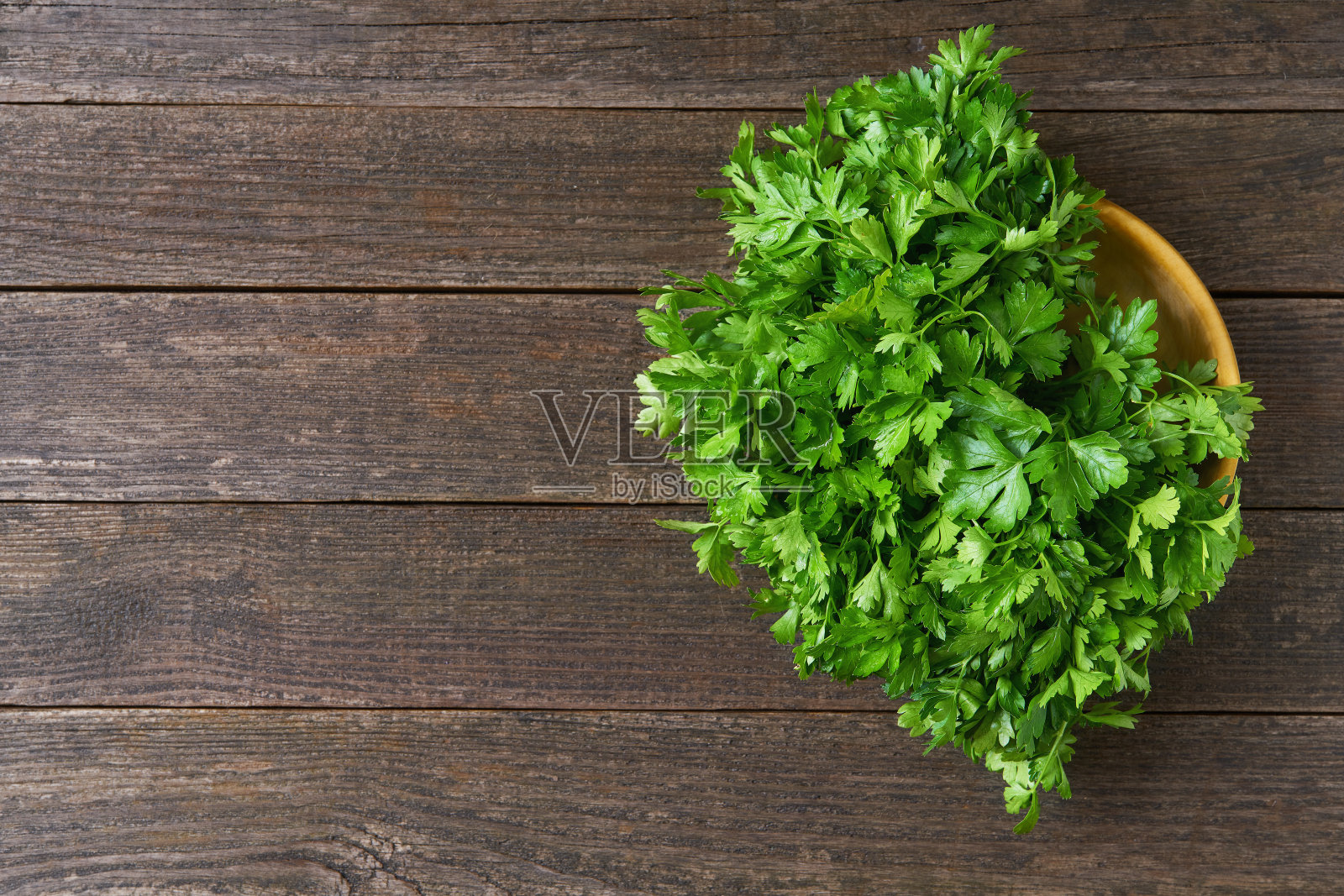 桌上的木碗里盛着新鲜的欧芹，俯视图。照片摄影图片