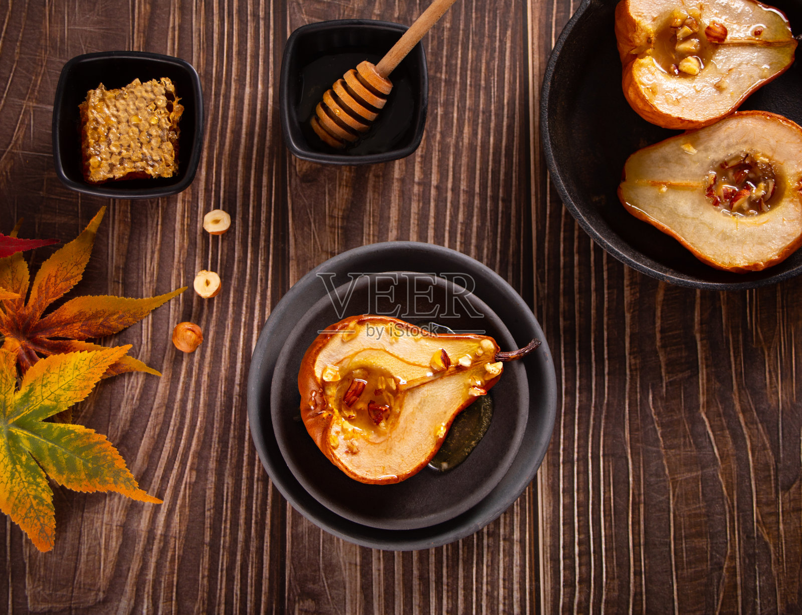 蜂蜜或枫糖浆烤梨配核桃。素食健康美味的甜点。照片摄影图片