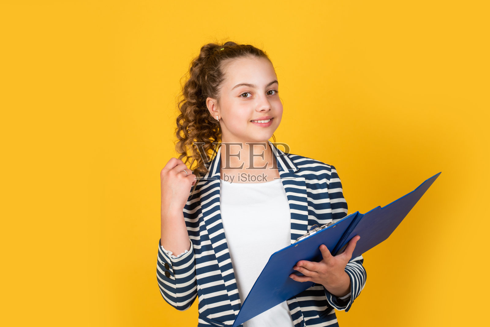 请在这里签名。小商人。快乐的童年。卷头发穿夹克的小孩。处理文件。女学生作业。回到学校。拿着办公室文件夹的小女孩照片摄影图片