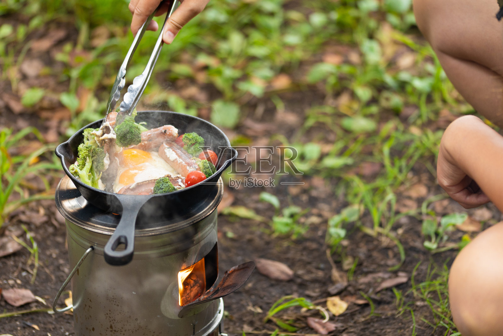 在篝火上用铸铁煎锅烹饪野营食物照片摄影图片