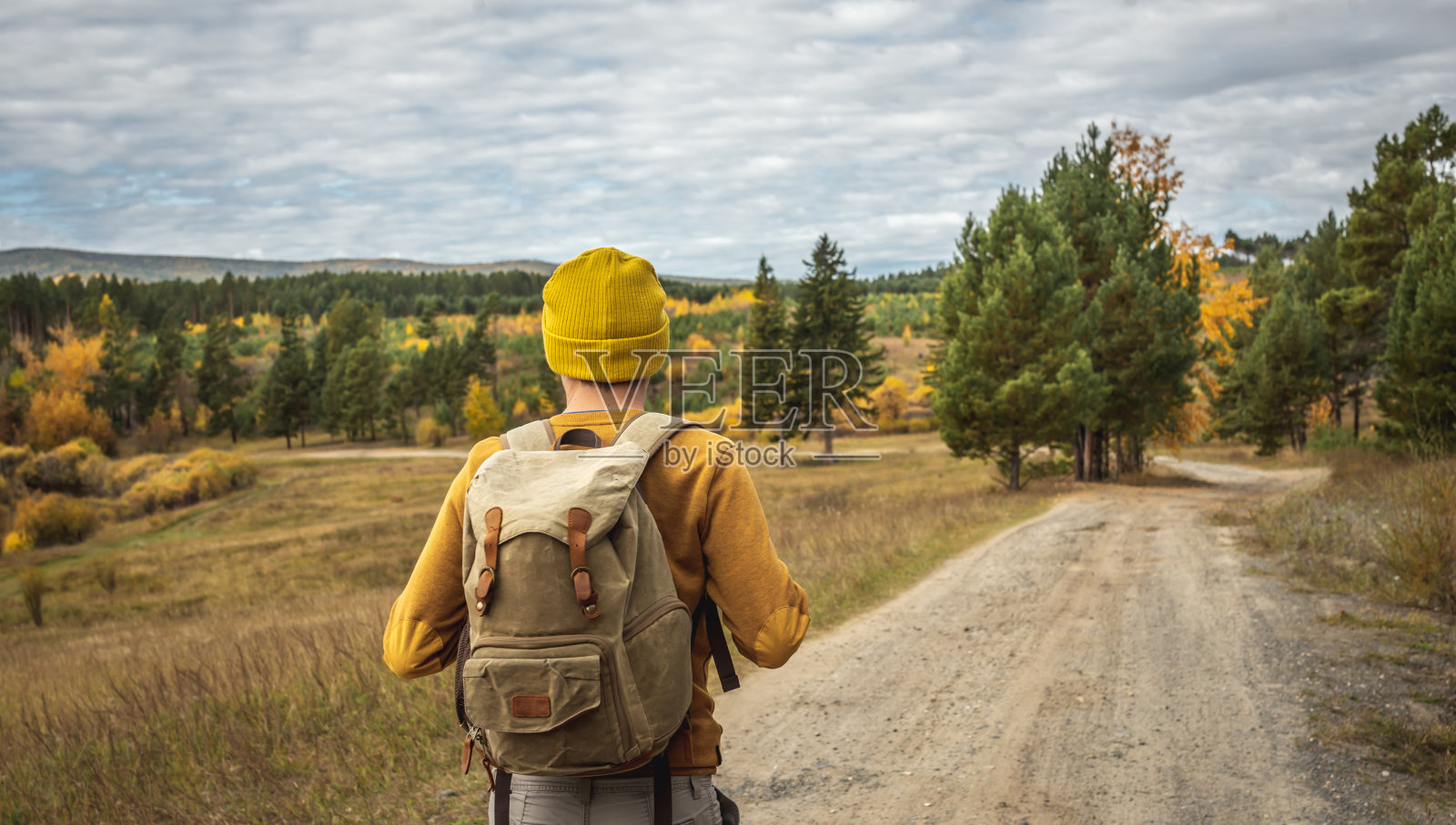 一个背着背包的旅行者走在一条空旷的森林小路上。自由的概念，旅行，远足和秋天的心情照片摄影图片