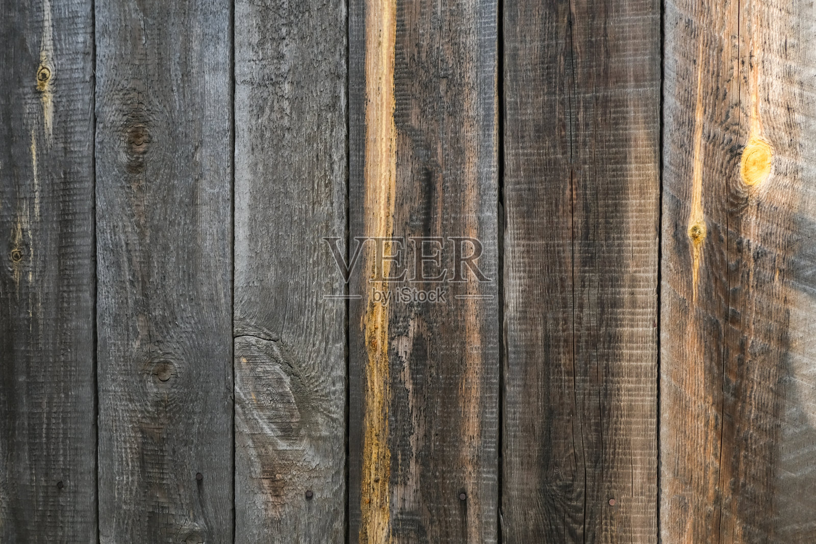 有阴影的旧篱笆的质地。木纹与垂直线。木材的纹理有结和孔。被时间损坏的栅栏的背景。照片摄影图片