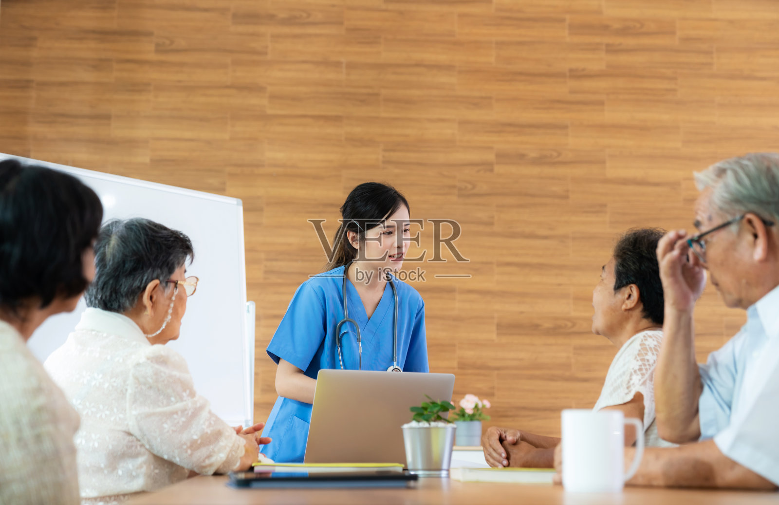 年轻的女护士，医生，护理人员使用笔记本电脑向养老院的老年病人解释处方处方药物。记录检查信息。医疗、制药和保险服务照片摄影图片