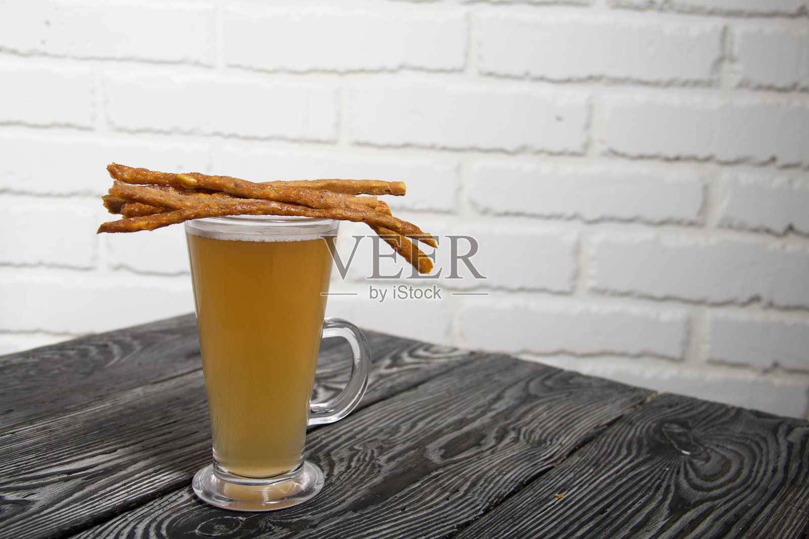 用细香肠换啤酒。他们躺在一杯小麦啤酒上。背景为松木板。特写镜头。照片摄影图片