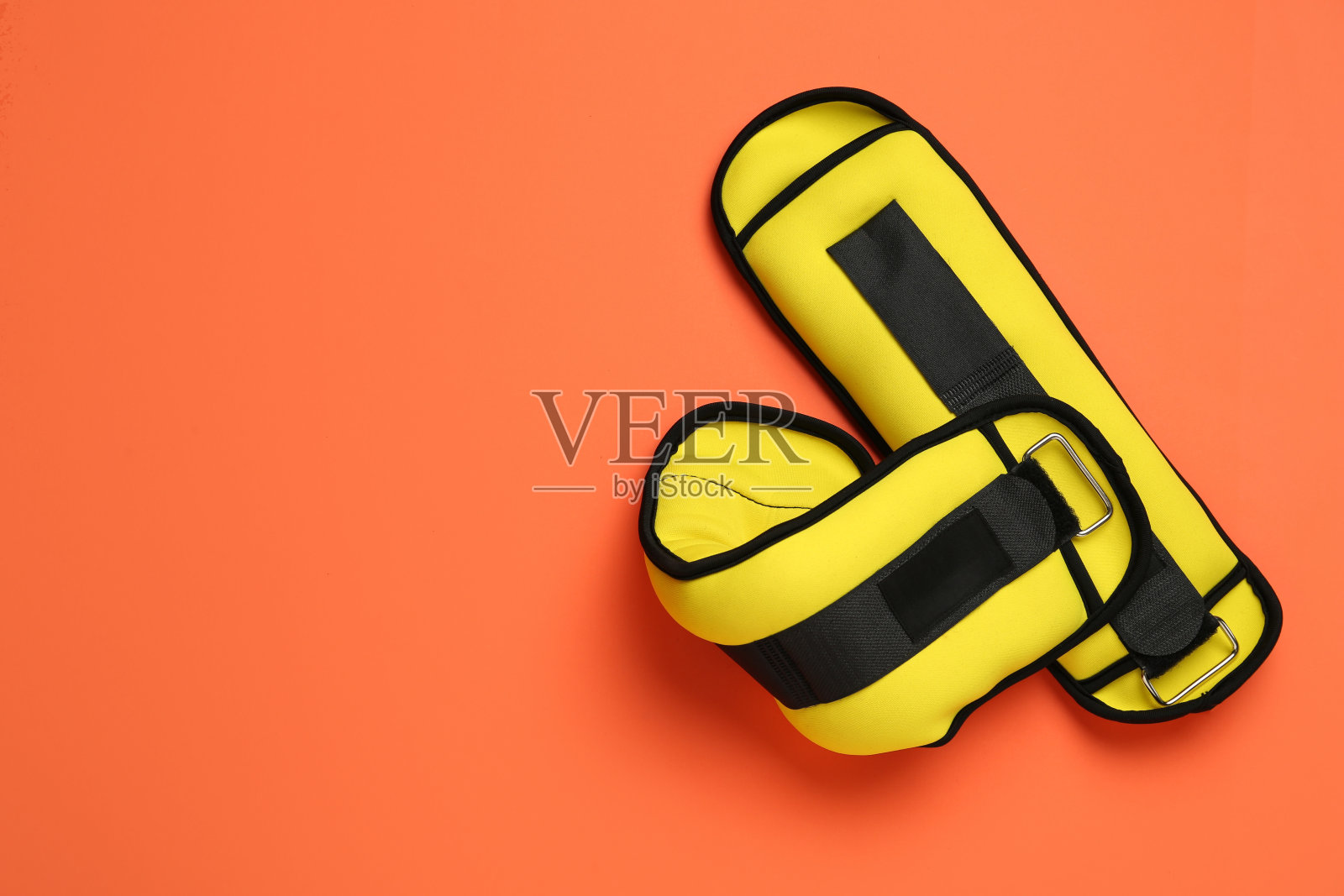 橙色背景下的黄色脚踝重量，平铺。空间的文本照片摄影图片