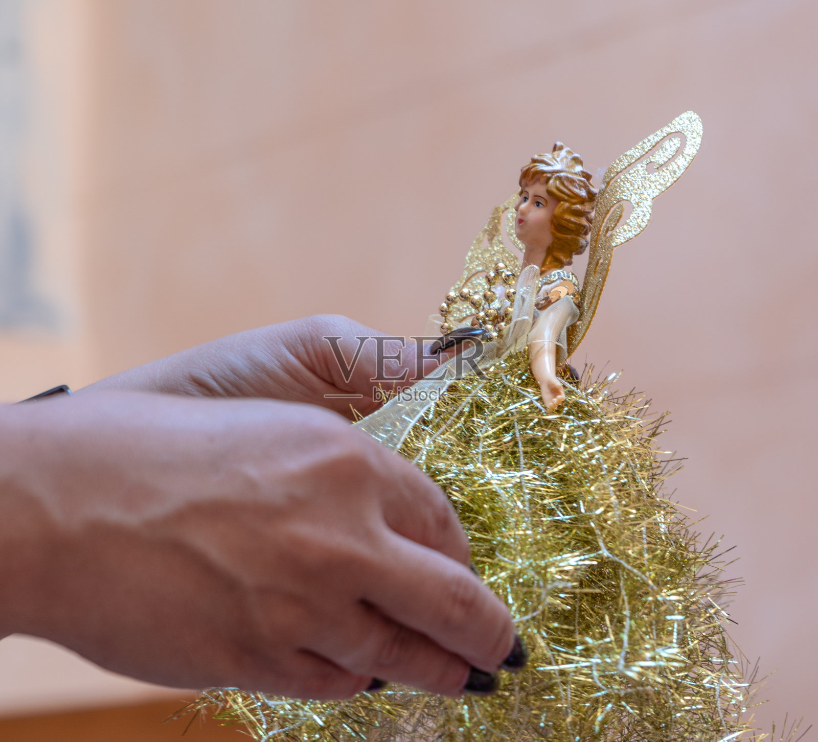 手里握着一个圣诞金色天使照片摄影图片