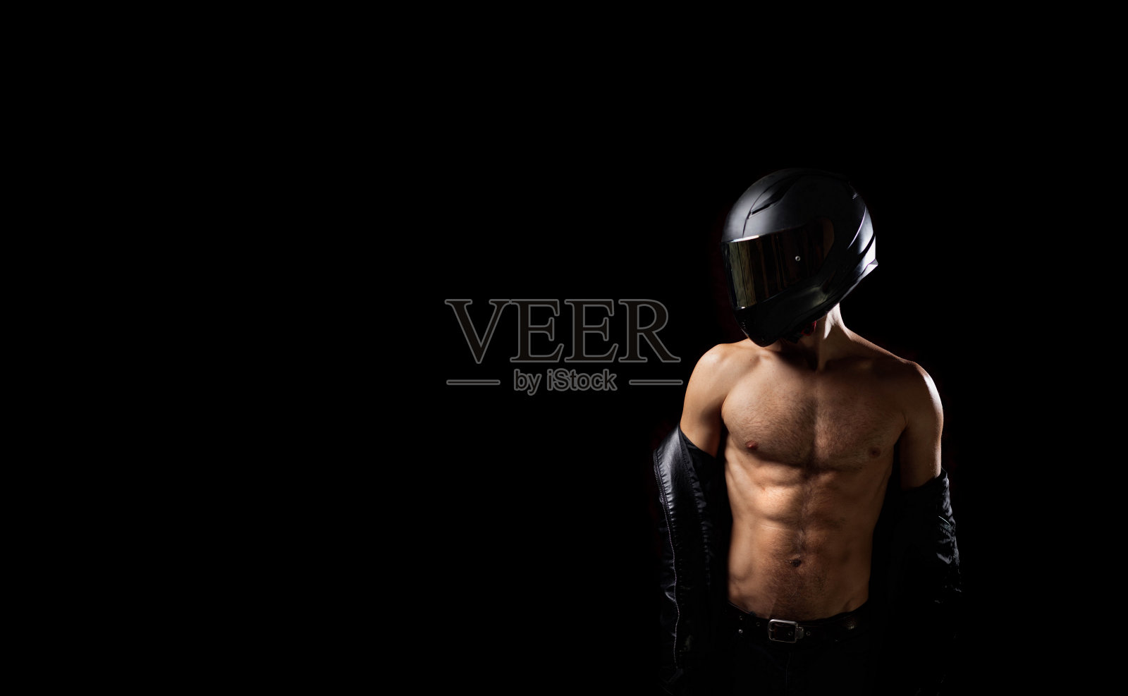 运动的男性摩托车手赤裸肌肉的身体在一个黑色背景的头盔。摩托车骑手的安全概念。照片摄影图片