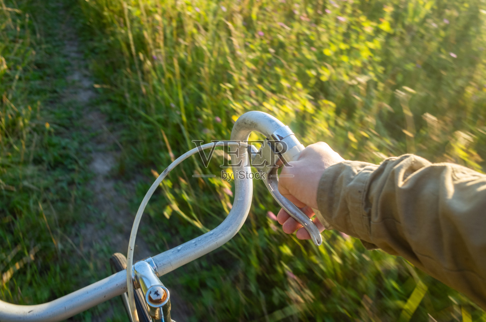 在大自然的乡间小路上骑自行车。控制自行车方向盘的手运动模糊照片摄影图片