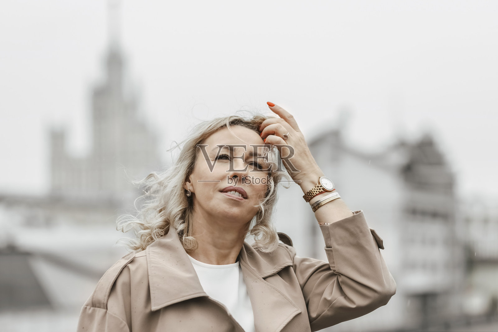 一位金发卷发的中年妇女站在城市的河堤上照片摄影图片