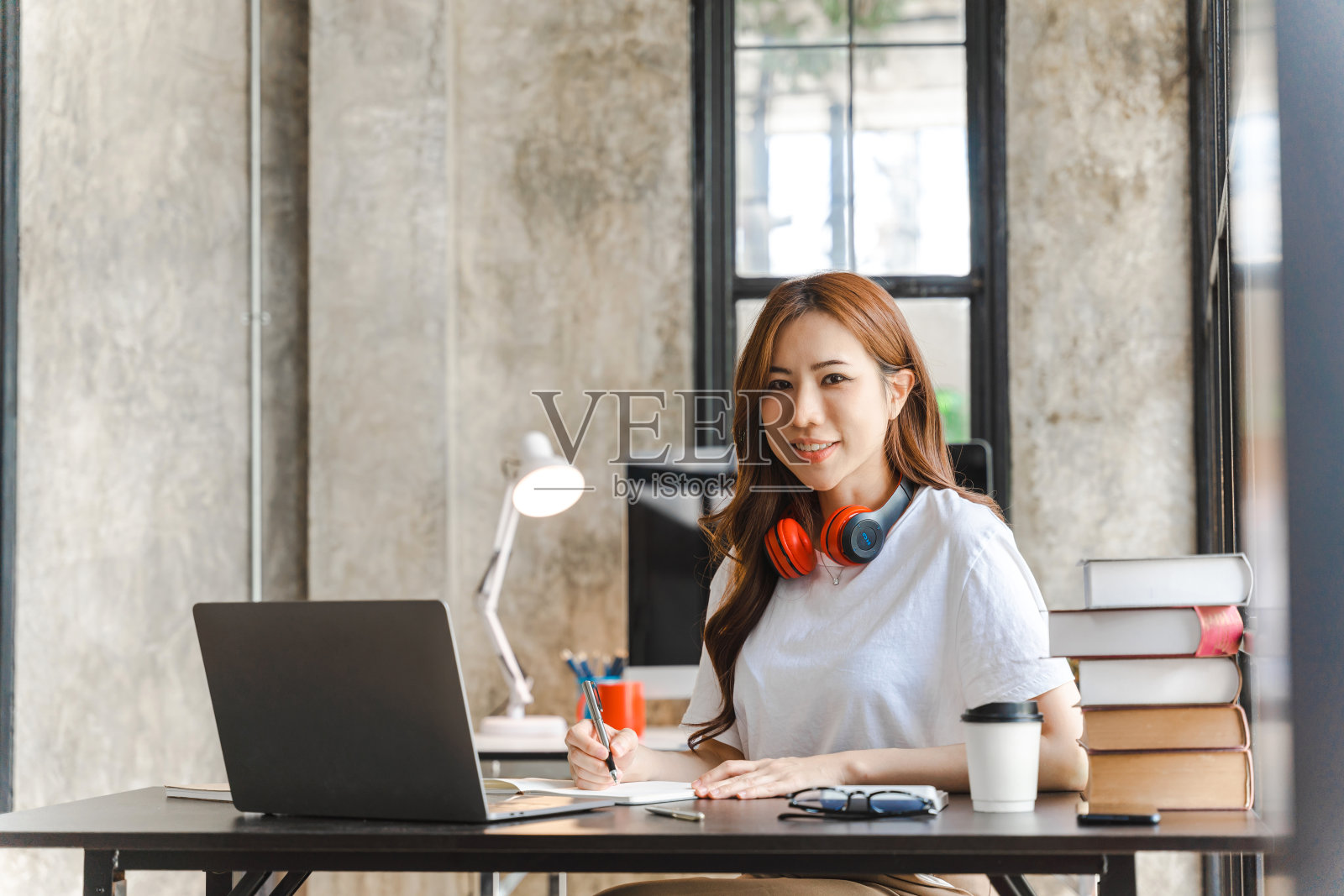 微笑的年轻亚洲女商人在家里使用电脑，办公室工作场所，快乐的韩国员工在笔记本电脑上工作。照片摄影图片