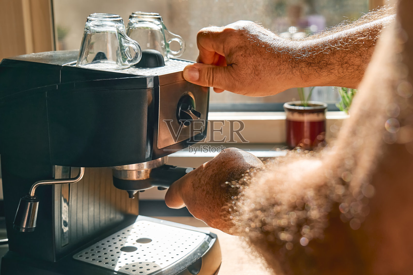 在家里厨房的浓缩咖啡机里，人们用手制作浓缩咖啡。觉醒热饮。早晨的习惯。照片摄影图片