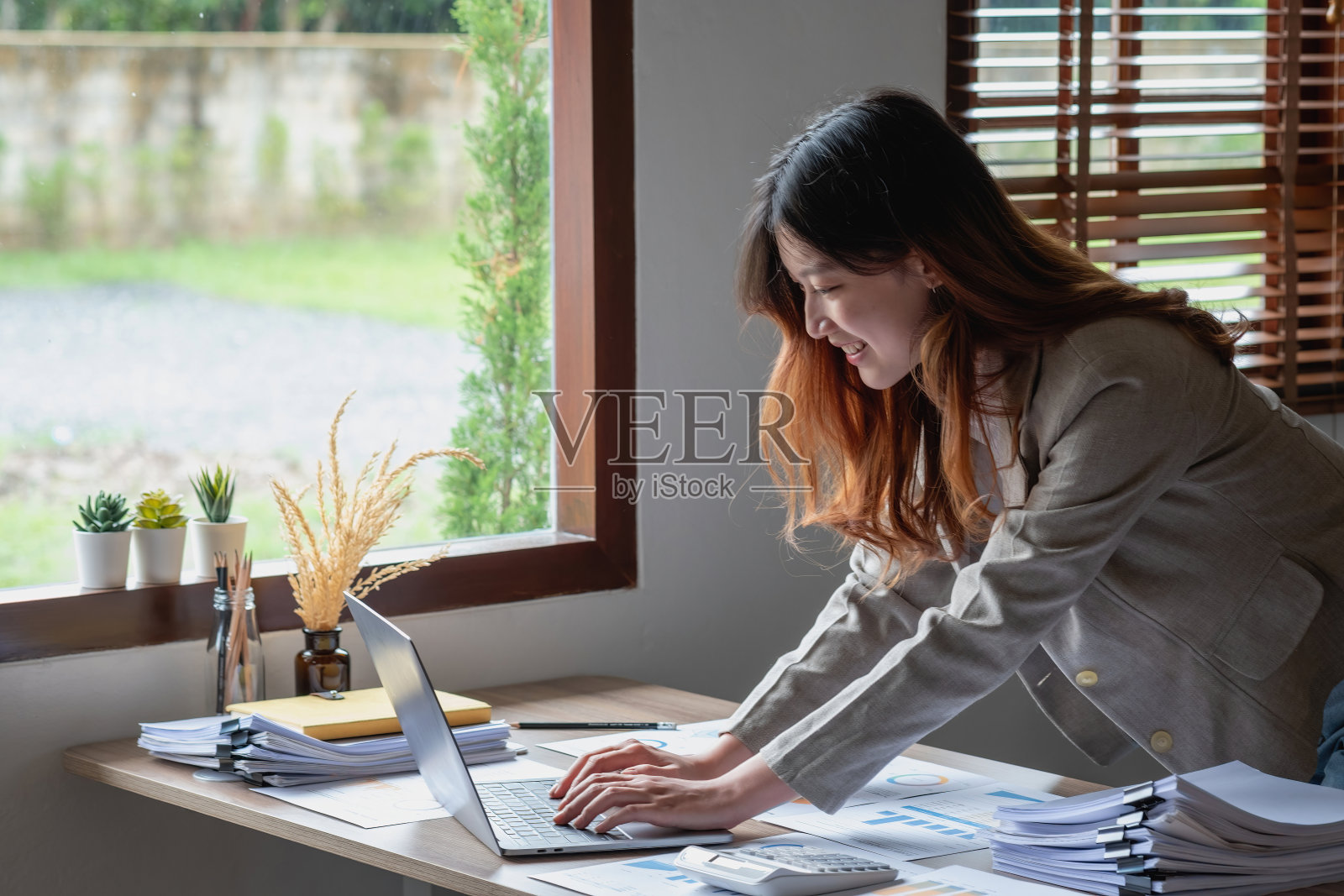 市场营销、财务、会计、计划、商业女性用图表统计分析公司的结果和利润。使用笔记本电脑和计算器来计算公司的结余。照片摄影图片
