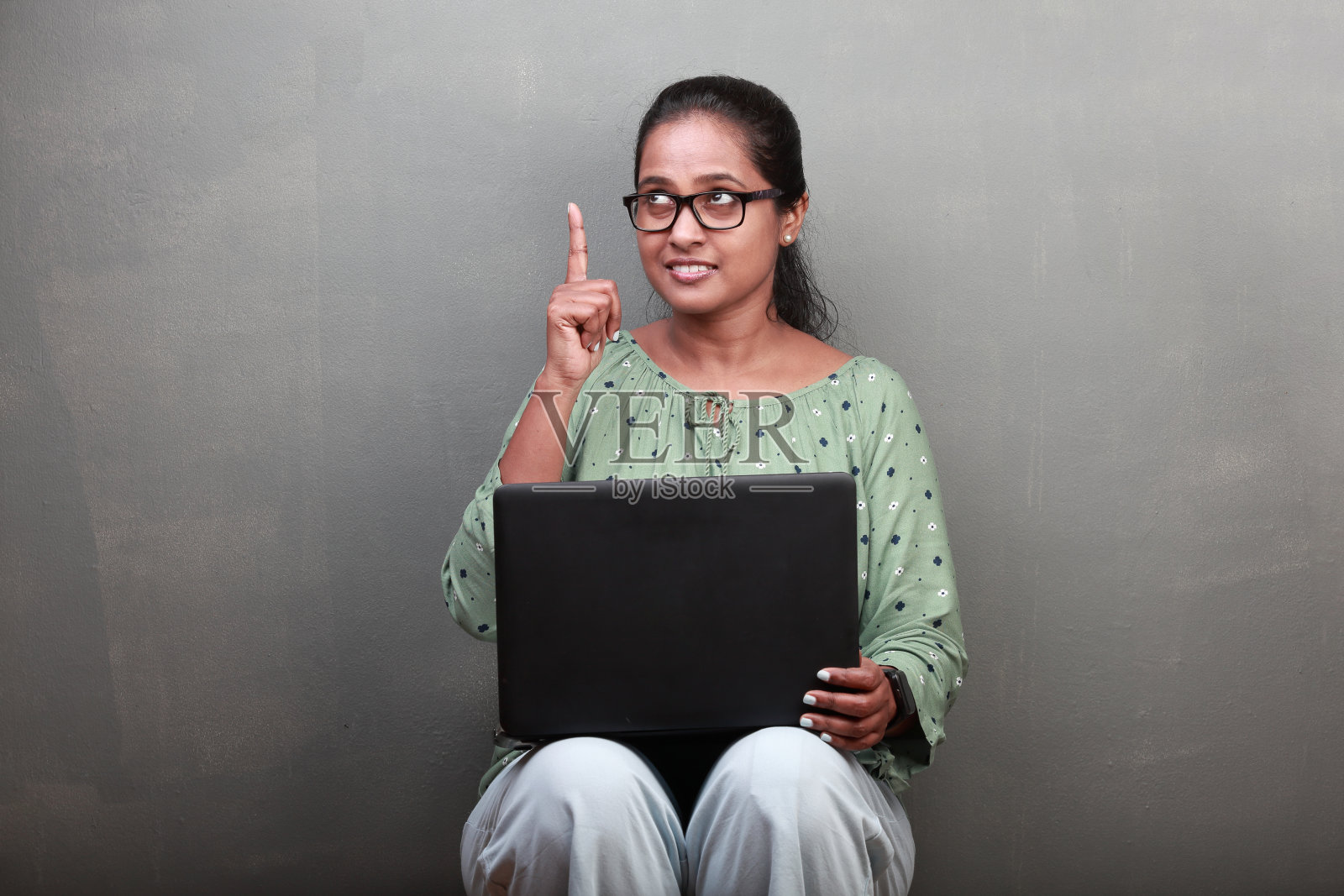 印度裔妇女，一脸沉思，手指朝上照片摄影图片