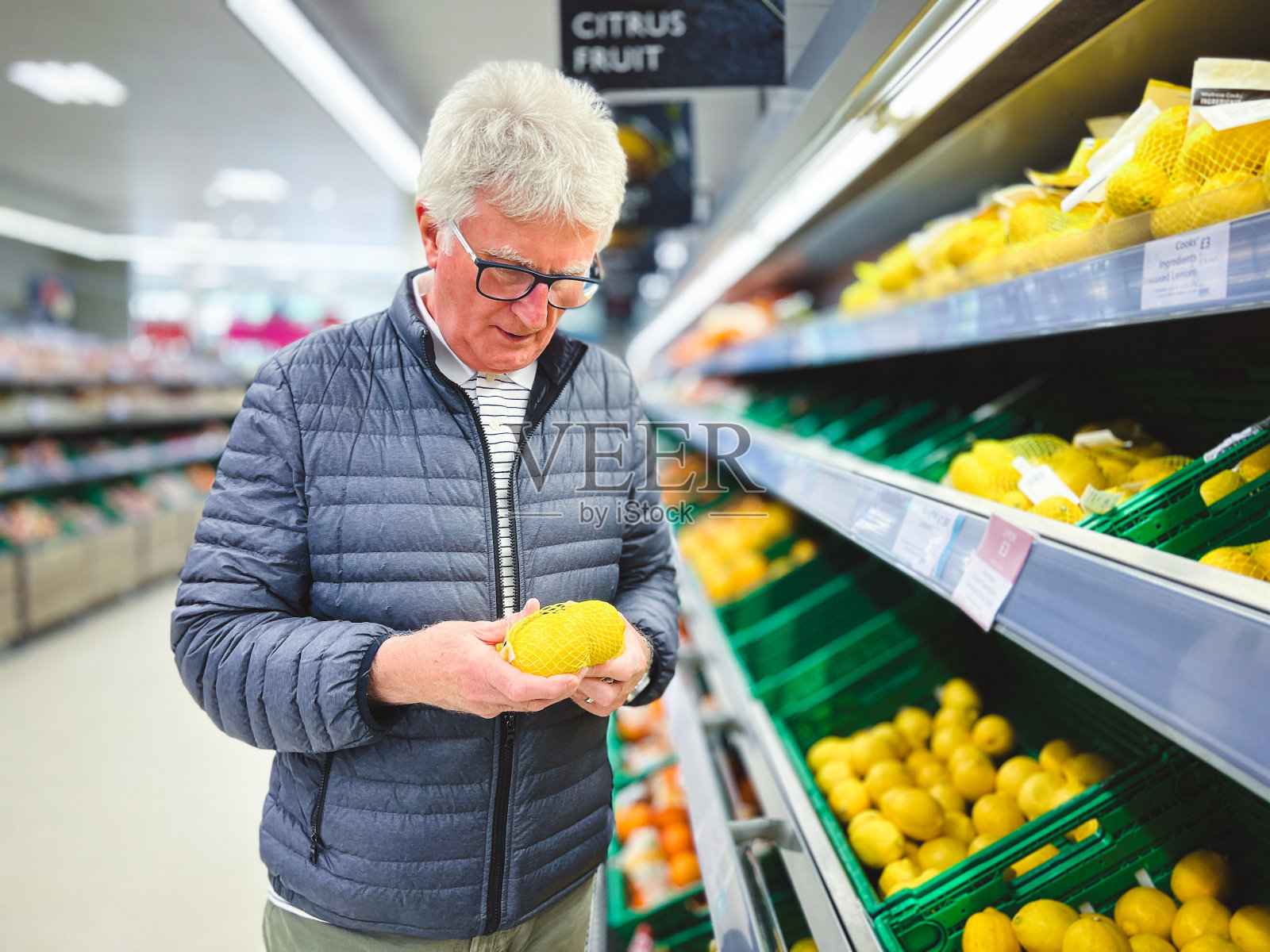 老人在超市里看柑橘类水果照片摄影图片