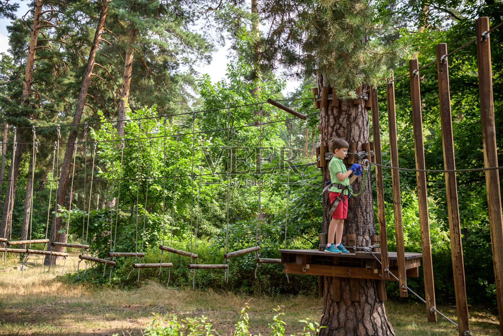 强壮兴奋的小男孩在户外玩绳公园。在温暖的阳光下，穿着休闲装和运动鞋的白人孩子。积极的休闲时间与孩子的概念照片摄影图片