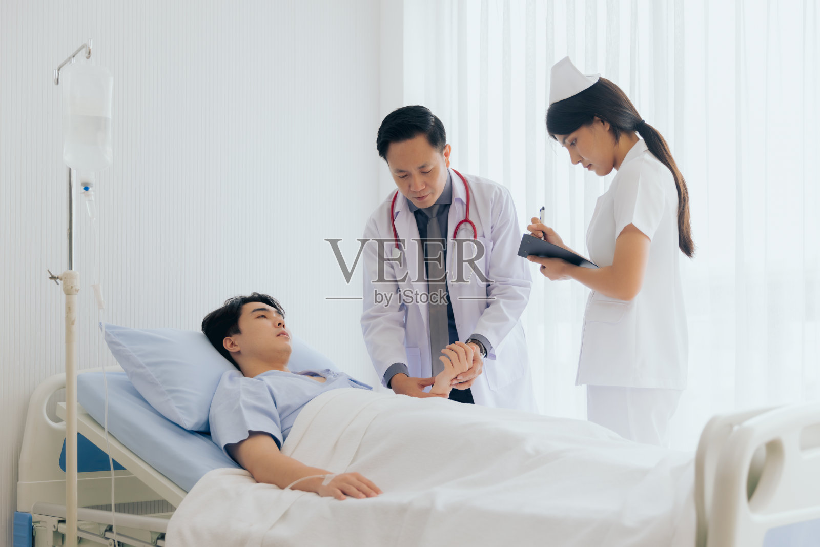 医生和护士在医院访问并使用听诊器检查男性患者的心跳照片摄影图片