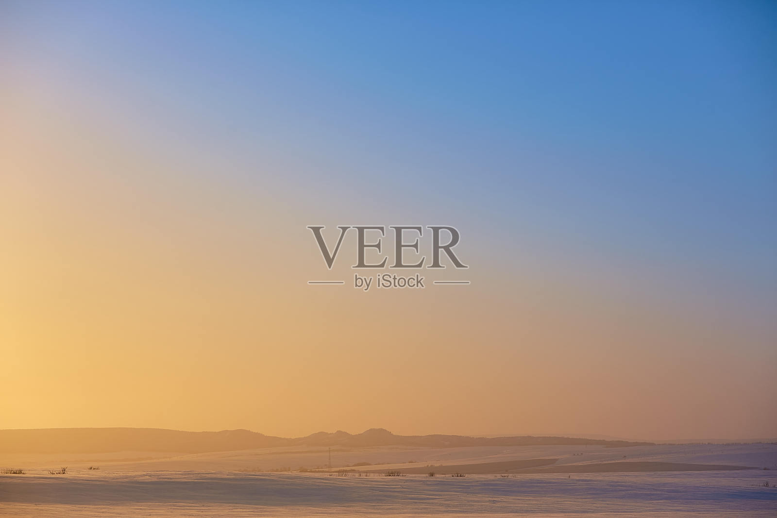 在冬天的雪中的树在日落时的蓝天背景下照片摄影图片