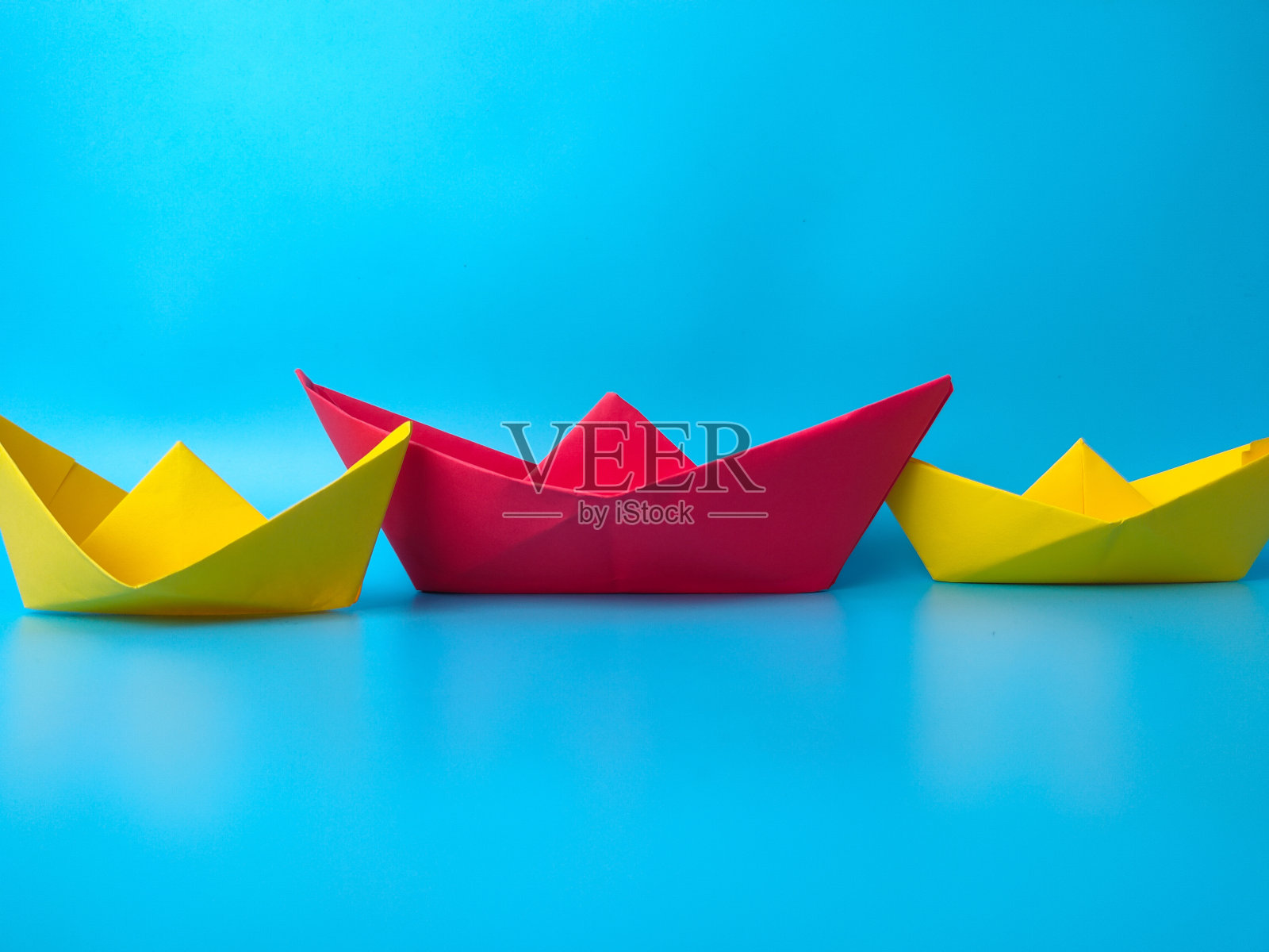 领导的概念。红色领航纸船在蓝色背景中领航。照片摄影图片