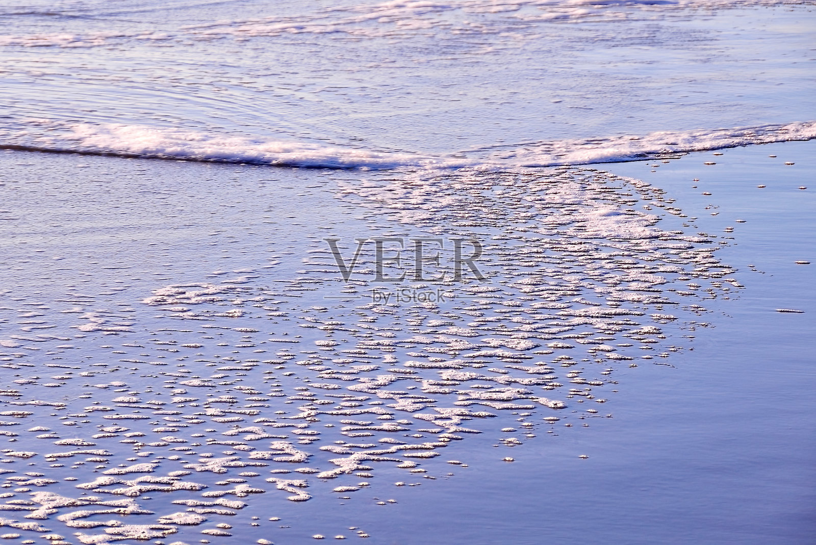 阳光照射下的海洋泡沫呈漩涡状照片摄影图片