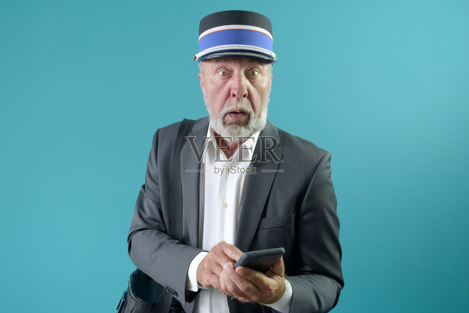 列车员担心火车的发车时间。浅蓝色的背景。照片摄影图片