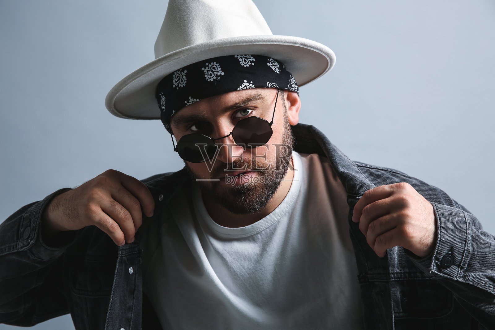 时髦的年轻人在时髦的服装与大手帕在灰色背景照片摄影图片