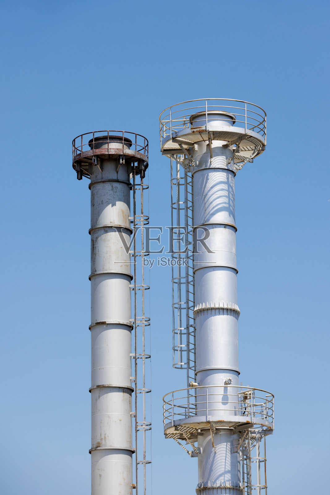 蓝色天空映衬着两座发电厂的金属烟囱塔照片摄影图片