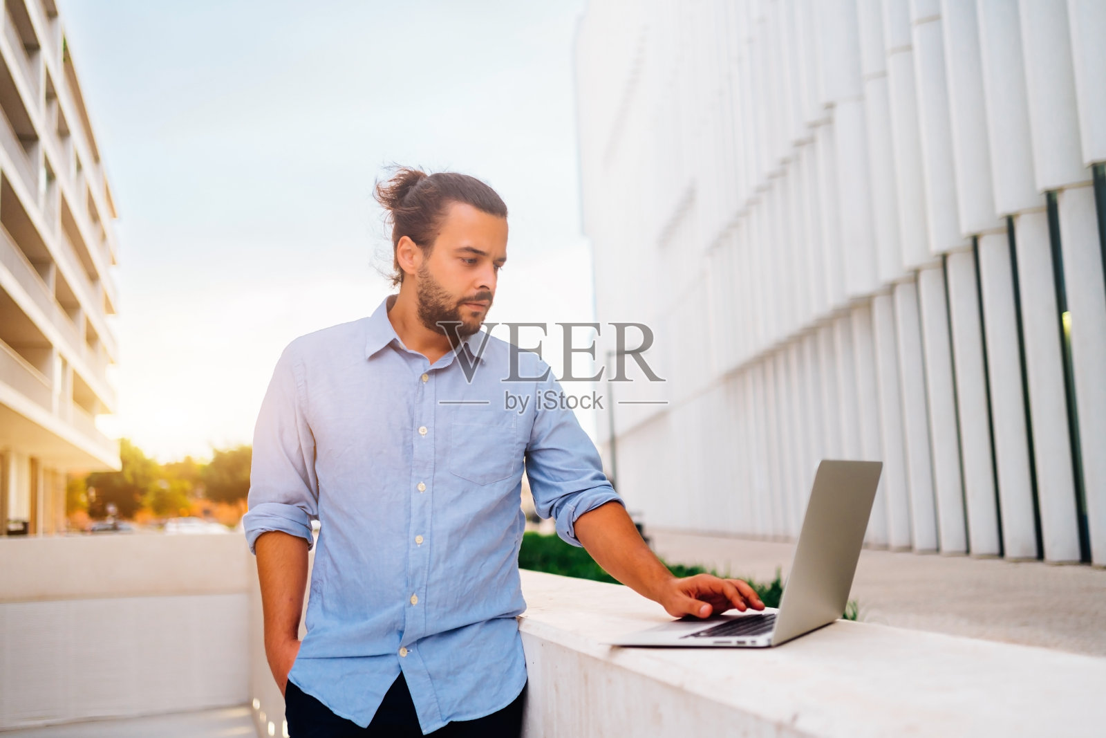 商人站在外面用笔记本电脑工作远程远程工作在户外附近的办公室照片摄影图片