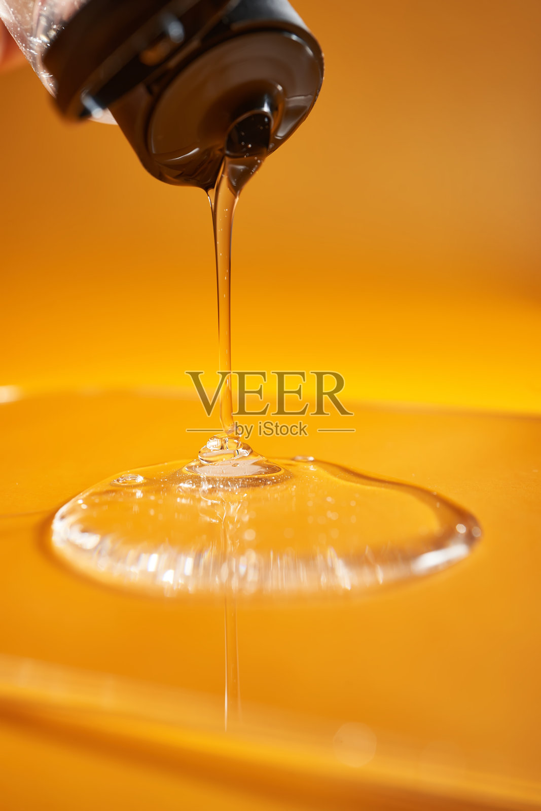 一滴身体啫喱或洗发水从上面洒在黄色饱和的背景上。照片摄影图片